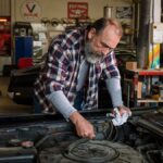 A mechanic handing a repair estimate to a customer considering a signature loan for car repair.