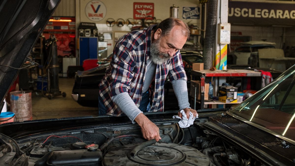 A mechanic handing a repair estimate to a customer considering a signature loan for car repair.